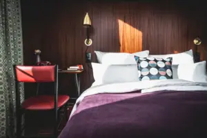 HENRI Düsseldorf A bed with pillows and a desk in a room.