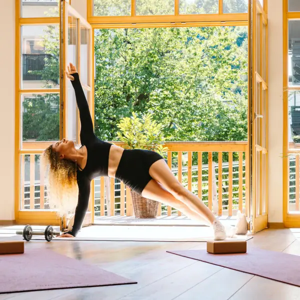 Fitness room A woman does a side plank in a room with windows.