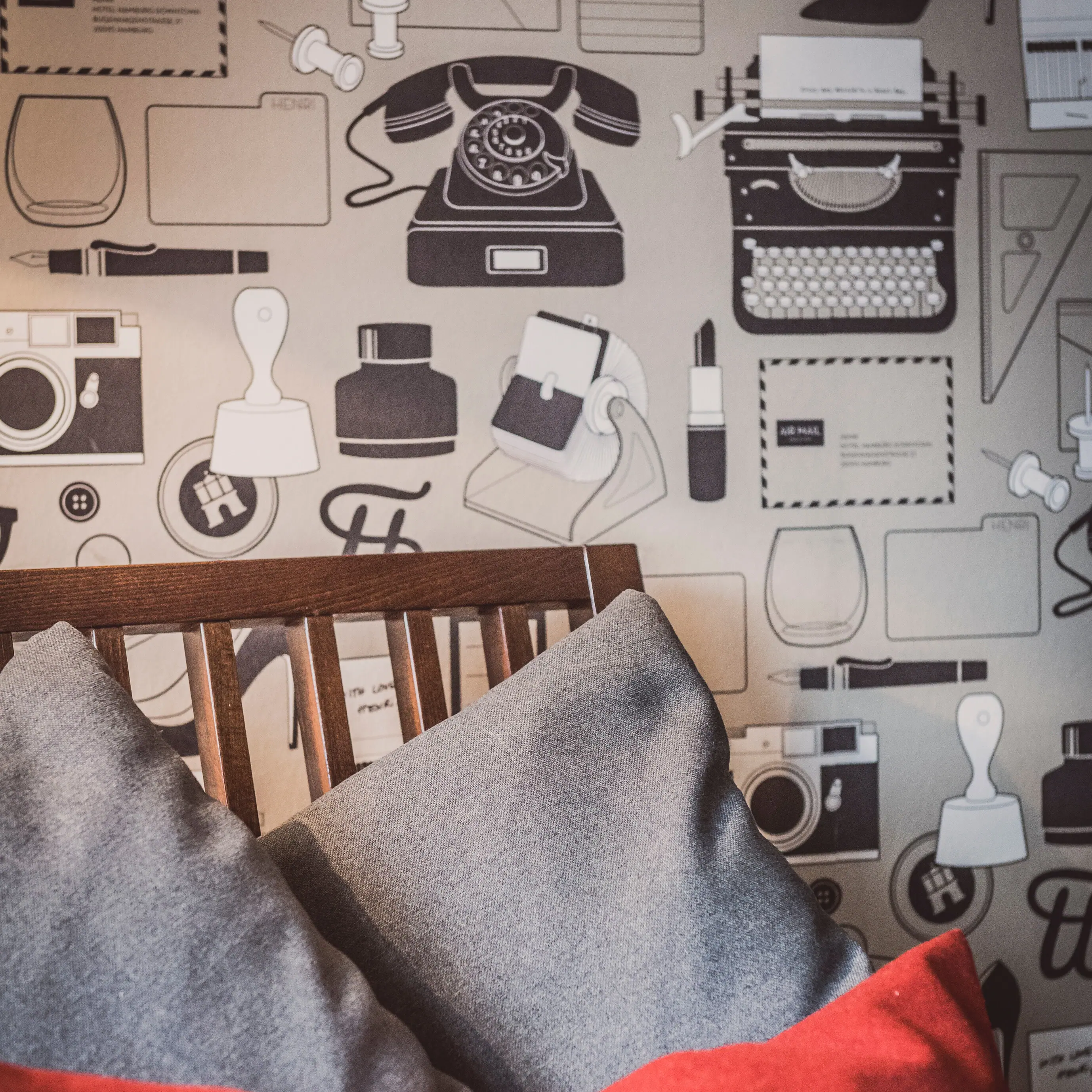 Armchair with cushions in front of a wall Armchair with grey and red cushions in front of a wall with motif wallpaper