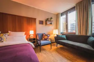 L-Studio HENRI Düsseldorf The L-Studio hotel room at the HENRI Hotel Düsseldorf with a bed and a sofa.