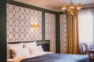 Vienna Hotel Room A bed with elegant bedding and a chandelier, framed by luxurious curtains.