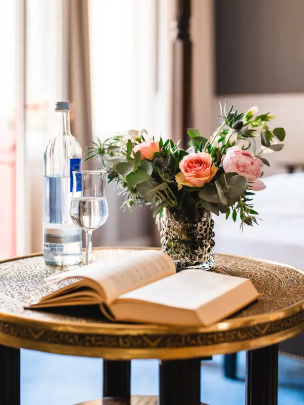 HENRI Hotel Berlin Deco Book Roses A book and a vase of flowers on a table.