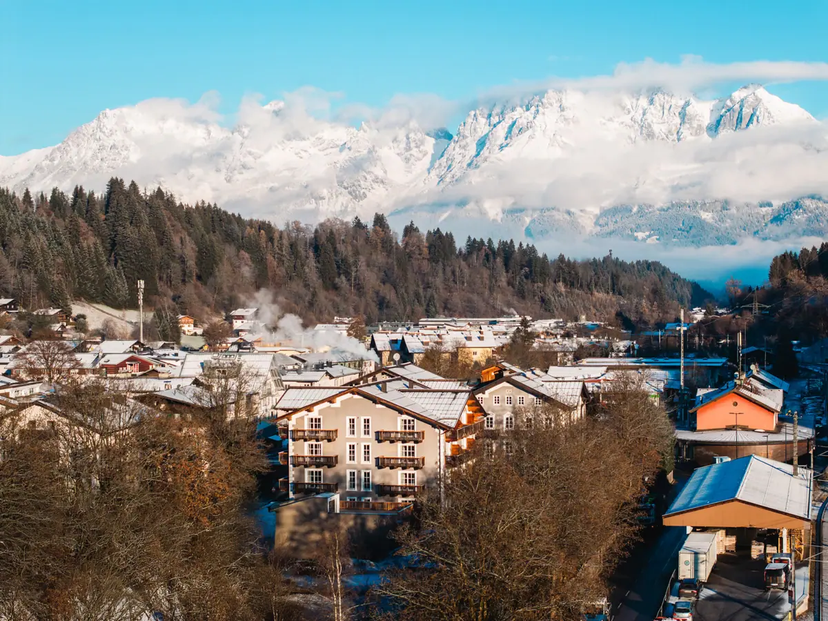 HENRI Kituzbühel A mountain village with snow-capped mountains in the background.