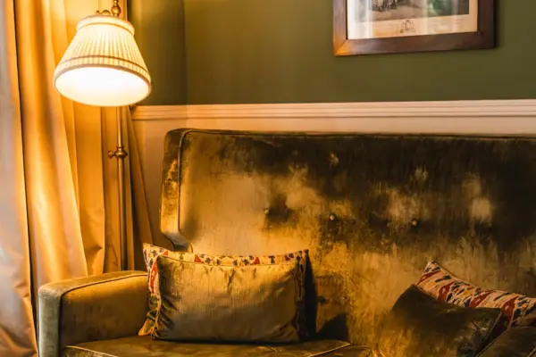 HENRI Berlin Room Couch A sofa with cushions and a lamp in a room.