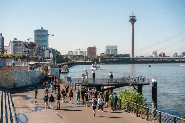 Düsseldorf Rhine bank A group of people are walking along a path near a body of water.