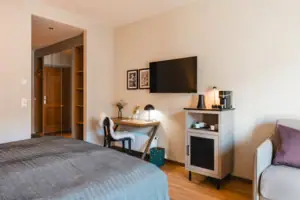 L-Studio Haus Ache HENRI Hotel Kitzbühel Bedroom with bed, desk and television.