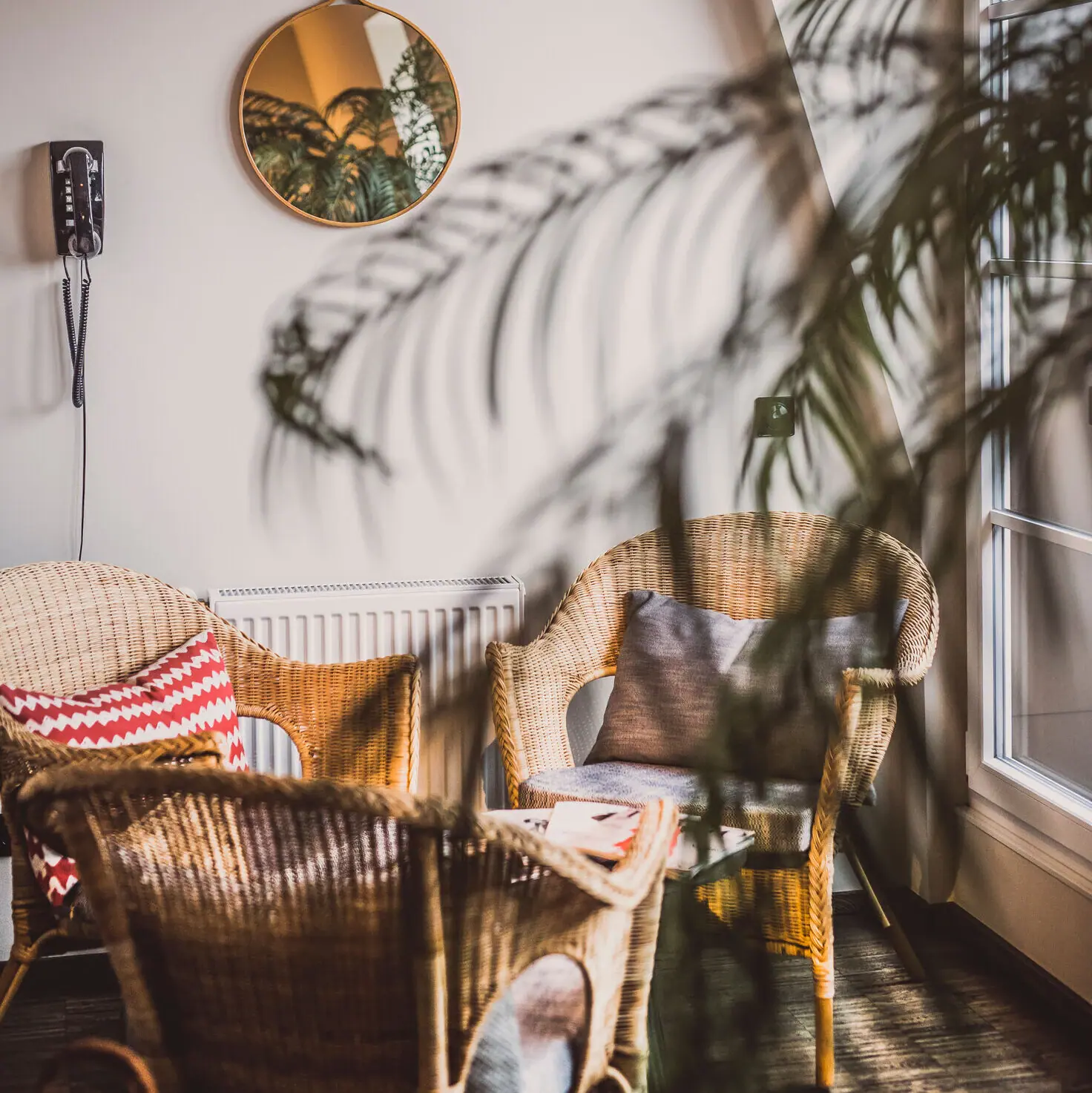 Sitting area in the wellness area of the HENRI Hotel Hamburg Wicker chairs with cushions in front of a white wall with a mirror.