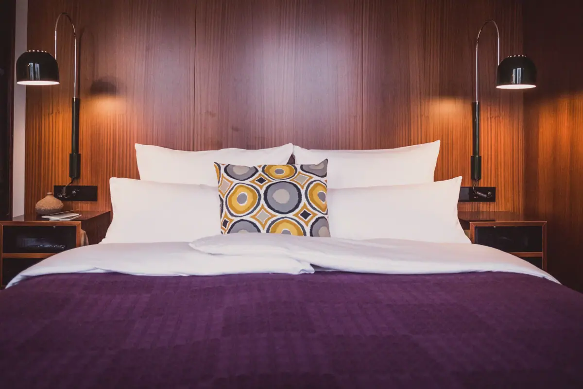 Rooms at the HENRI Hotel Düsseldorf A bed with pillows and a lamp.