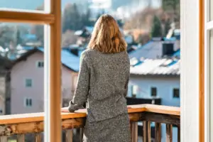 L-Studio Haus Ache HENRI Hotel Kitzbühel A woman looks out of a window at a mountain range.