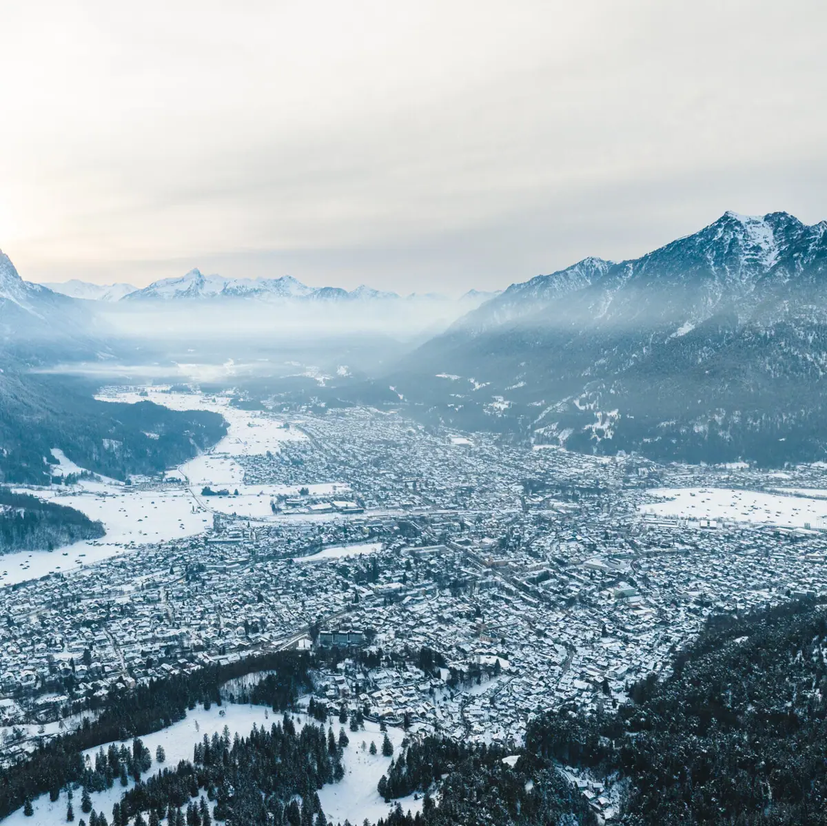 Garmisch-Partenkirchen in winter A snow-covered city with mountains in the background.