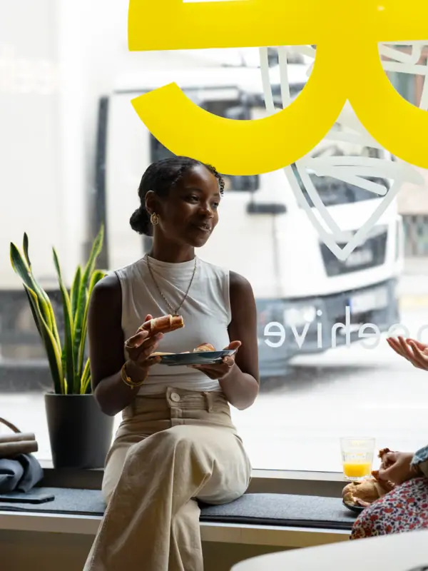 Beehive Düsseldorf A woman sits on a windowsill and eats.