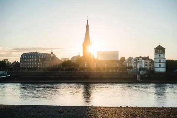 City next to a river Water surface with buildings and a tower in the background.