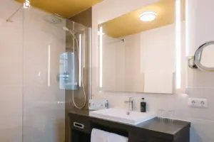 Bathroom at the HENRI Hotel Garmisch-Partenkirchen A bathroom with washbasin and mirror at the HENRI Hotel Garmisch-Partenkirchen.
