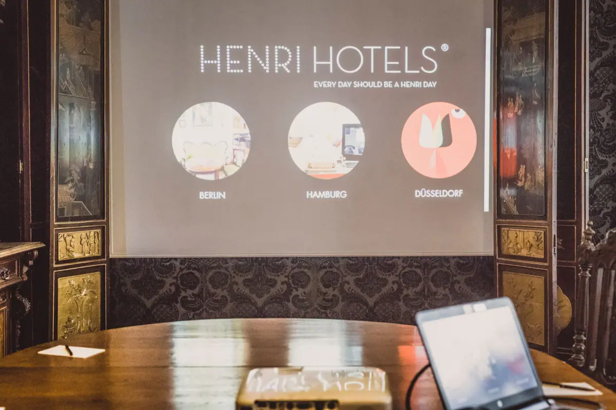 HENRI Berlin presentation area Projector on a wooden table with a screen in front of it