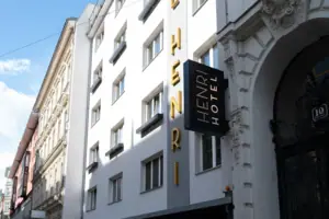 HENRI Hotel Vienna Sign on a building facade with windows and a cloudy sky in the background.