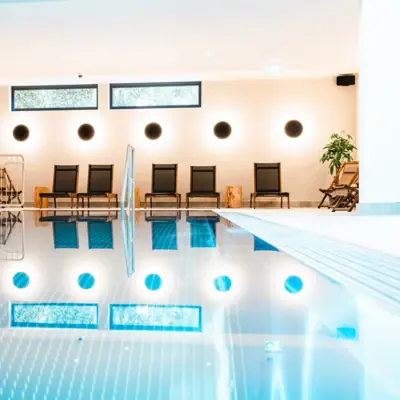 Indoor swimming pool at the HENRI Hotel Kitzbühel A swimming pool with steps and deckchairs.