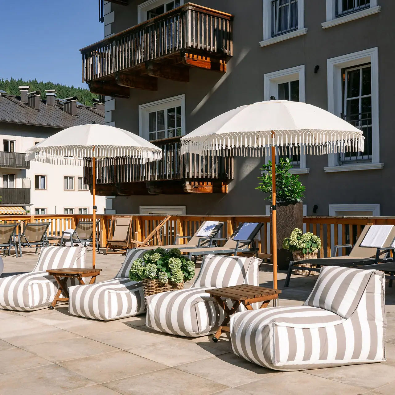 Sun terrace of the HENRI Hotel Kitzbühel A patio with chairs and parasols.