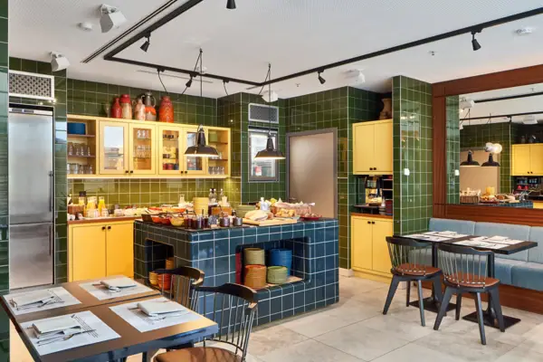 HENRI Düsseldorf A room with green tiles and yellow cupboards.