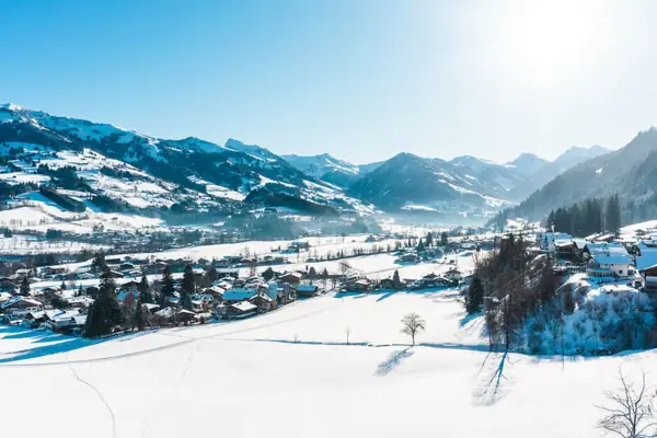 Kitzbühel in winter Snow-covered landscape with houses and mountains in the background.