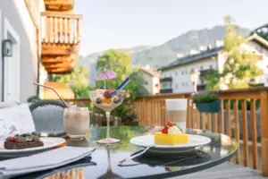 HENRI Kitzbühel Terrasse Ein Tisch mit einem Getränk und Dessert darauf.
