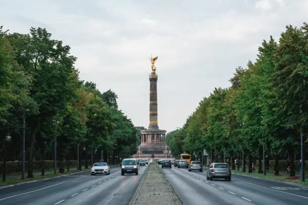 Berlin Street with cars and a statue on top