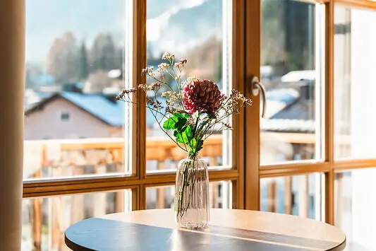 View A bouquet of flowers in a vase on a table next to a window.