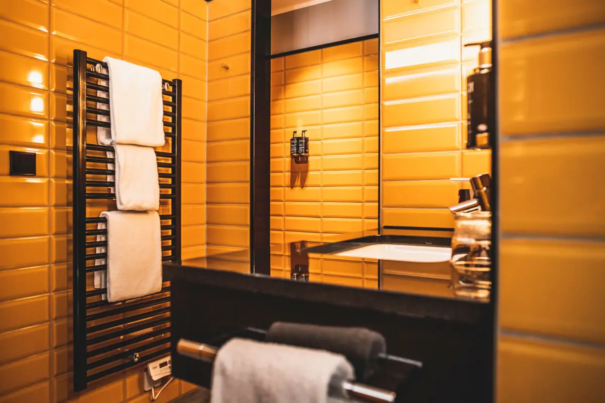 Bathroom at the HENRI Hotel Düsseldorf Bathroom with yellow tiled walls and a mirror