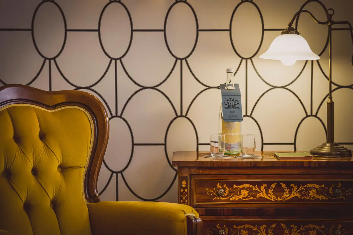 Room detail A chair and a table with glasses and a bottle on it.