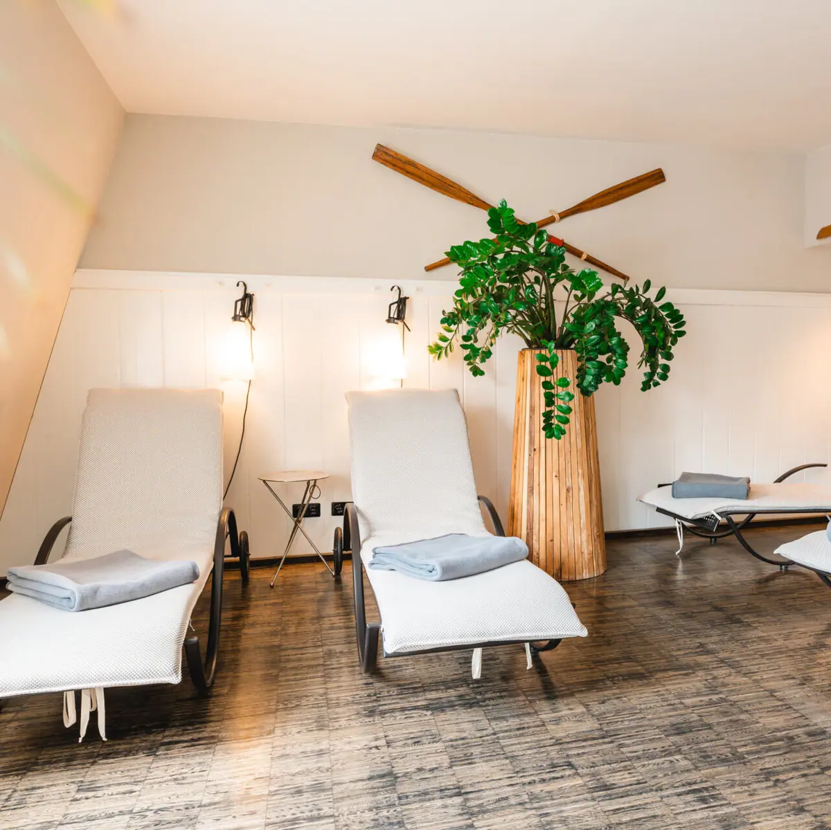 Loungers in the wellness area of the HENRI Hotel Hamburg Deckchairs with cosy cushions and a large green houseplant