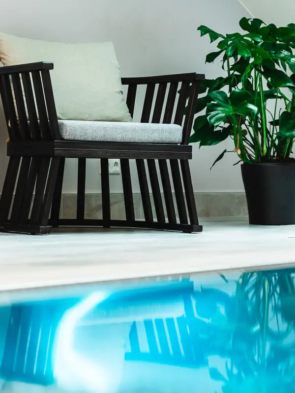 Chairs by the indoor pool at the HENRI Kitzbühel A chair and a plant next to a pool.