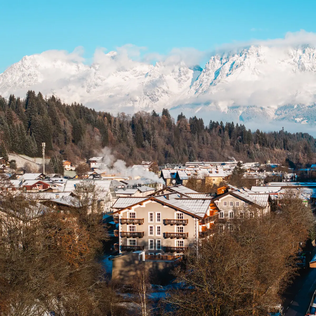 HENRI Hotel Kitzbühel The town of Kitzbühel in winter with snow-covered mountains in the background.