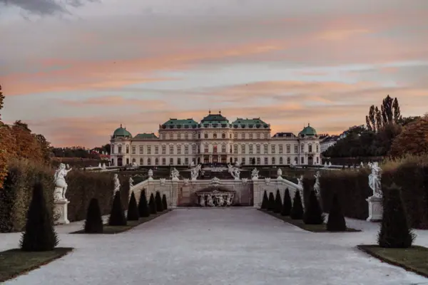 Belvedere Palace A large white building with a fountain and a pavement in the foreground.
