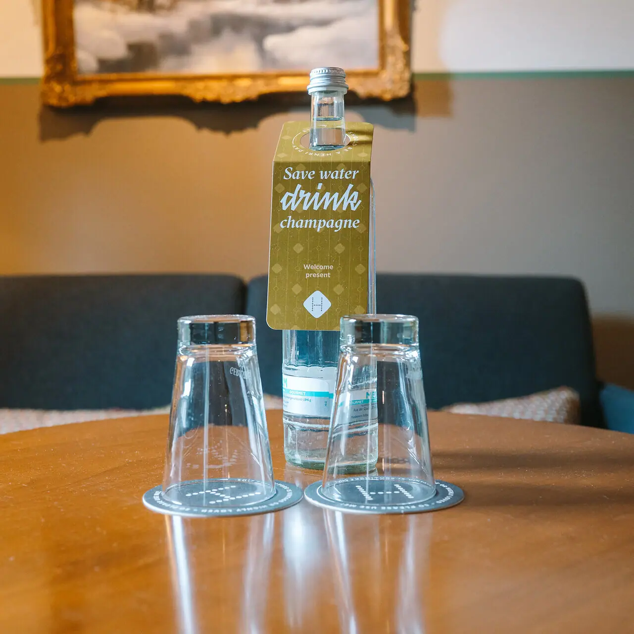 Water bottle in the HENRI hotel room A bottle and glasses on a table.