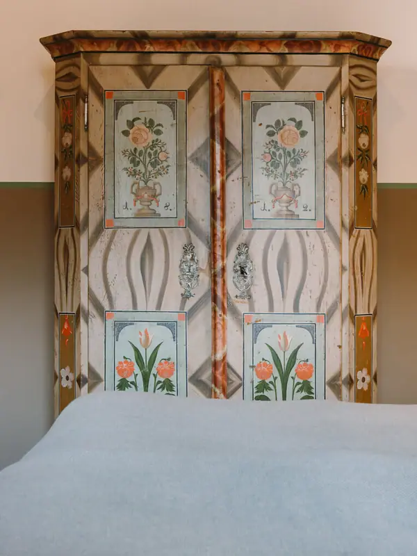 Old cupboard HENRI Garmisch-Partenkirchen A bed with a painted wardrobe in the background.