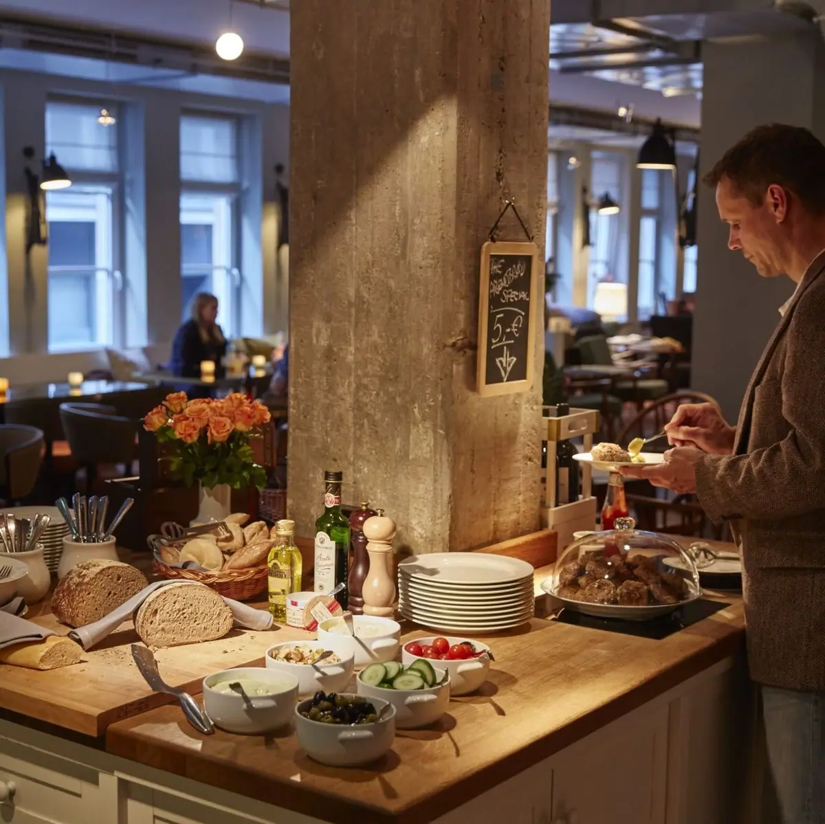 Evening meal HENRI Hamburg A man stands at a bar eating dinner and puts something on his plate.