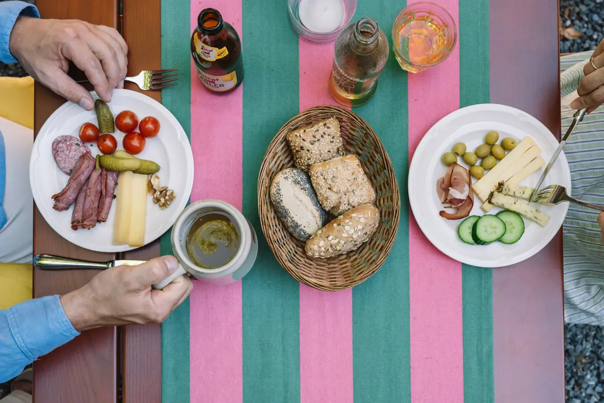 Table with food Person holding a cup and a plate of food.