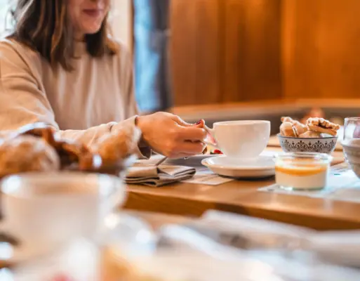 Breakfast table at HENRI A woman holds a teacup at a breakfast table.
