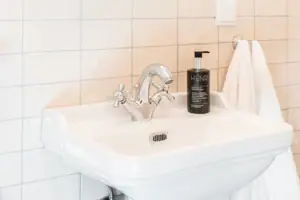 Bathroom HENRI Kitzbühel Mirror above a washbasin with a flower in a vase