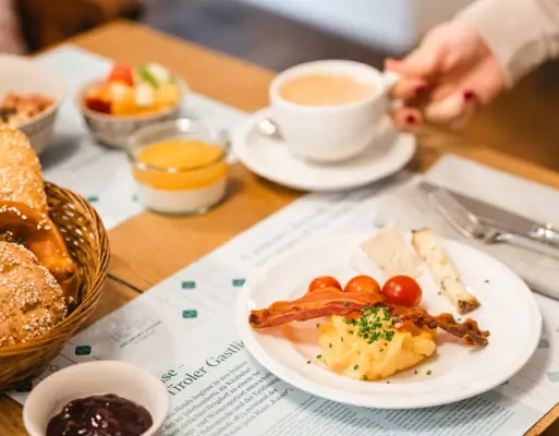 Breakfast table HENRI Hotel One person is holding a cup of coffee and a plate of food.