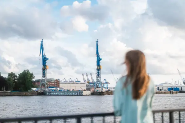 View of Hamburg harbour A woman stands at a religious building and looks across the Elbe towards Hamburg harbour