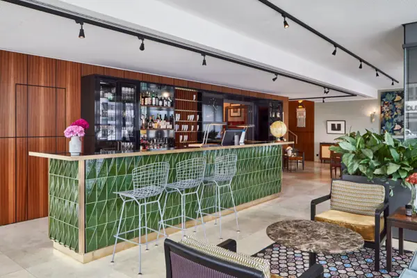 HENRI Düsseldorf A bar with green tiles and chairs.