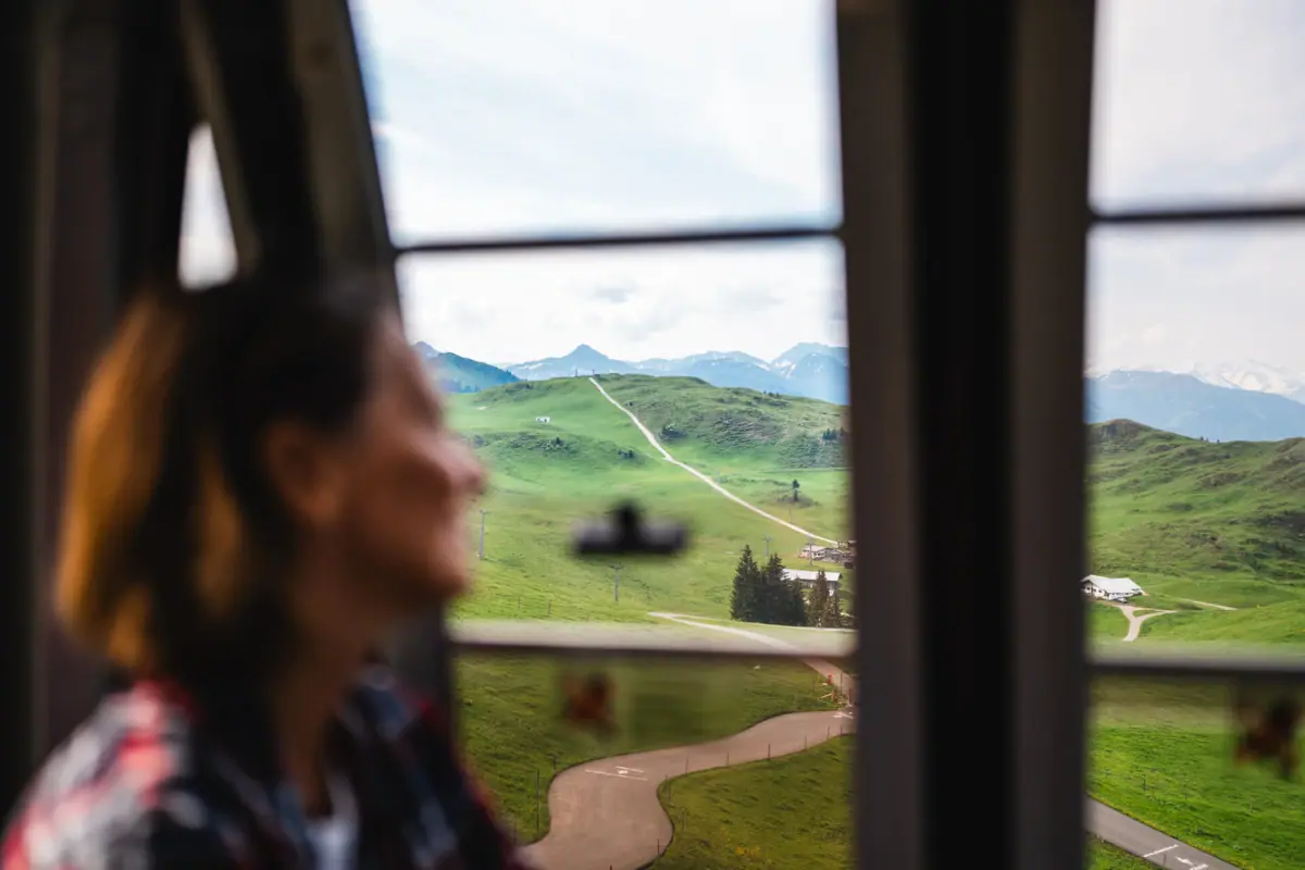 HENRI KIZ Summer A woman looks out of a window at a landscape.