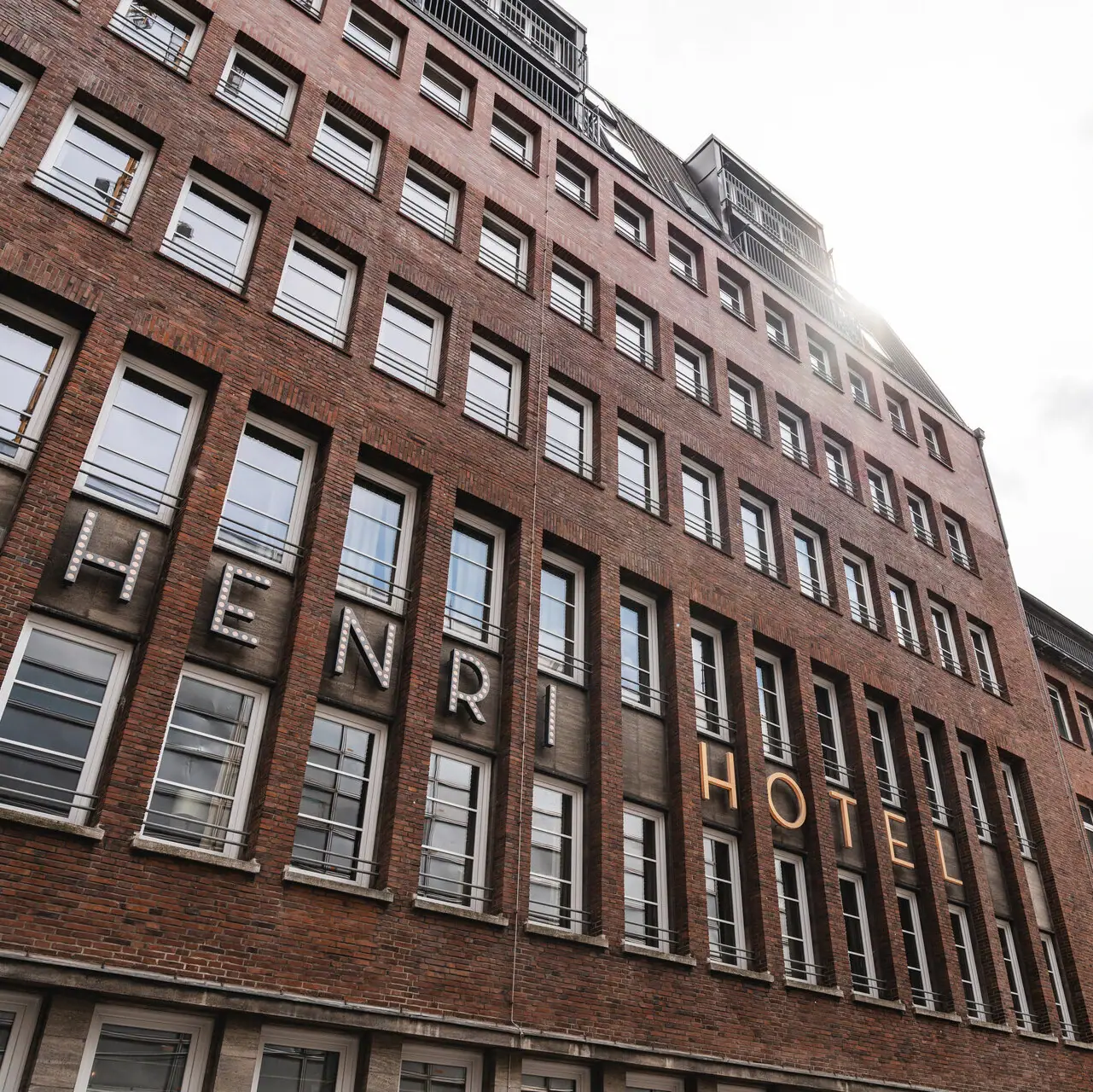 HENRI Hamburg A building with a high tower in front of a cloudy sky.