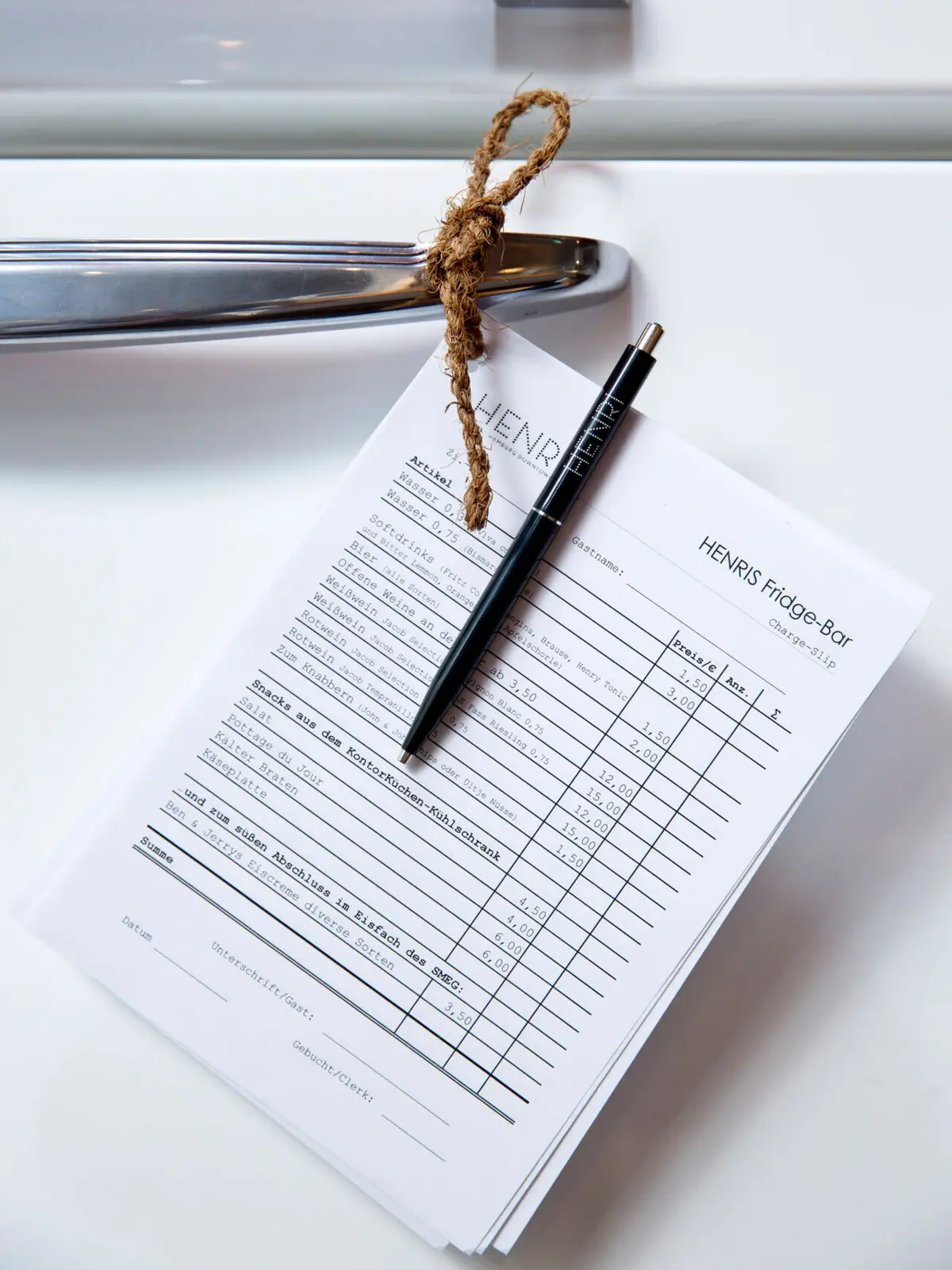 HENRIS Fridge Bar A pen on a piece of paper hangs on a fridge door.