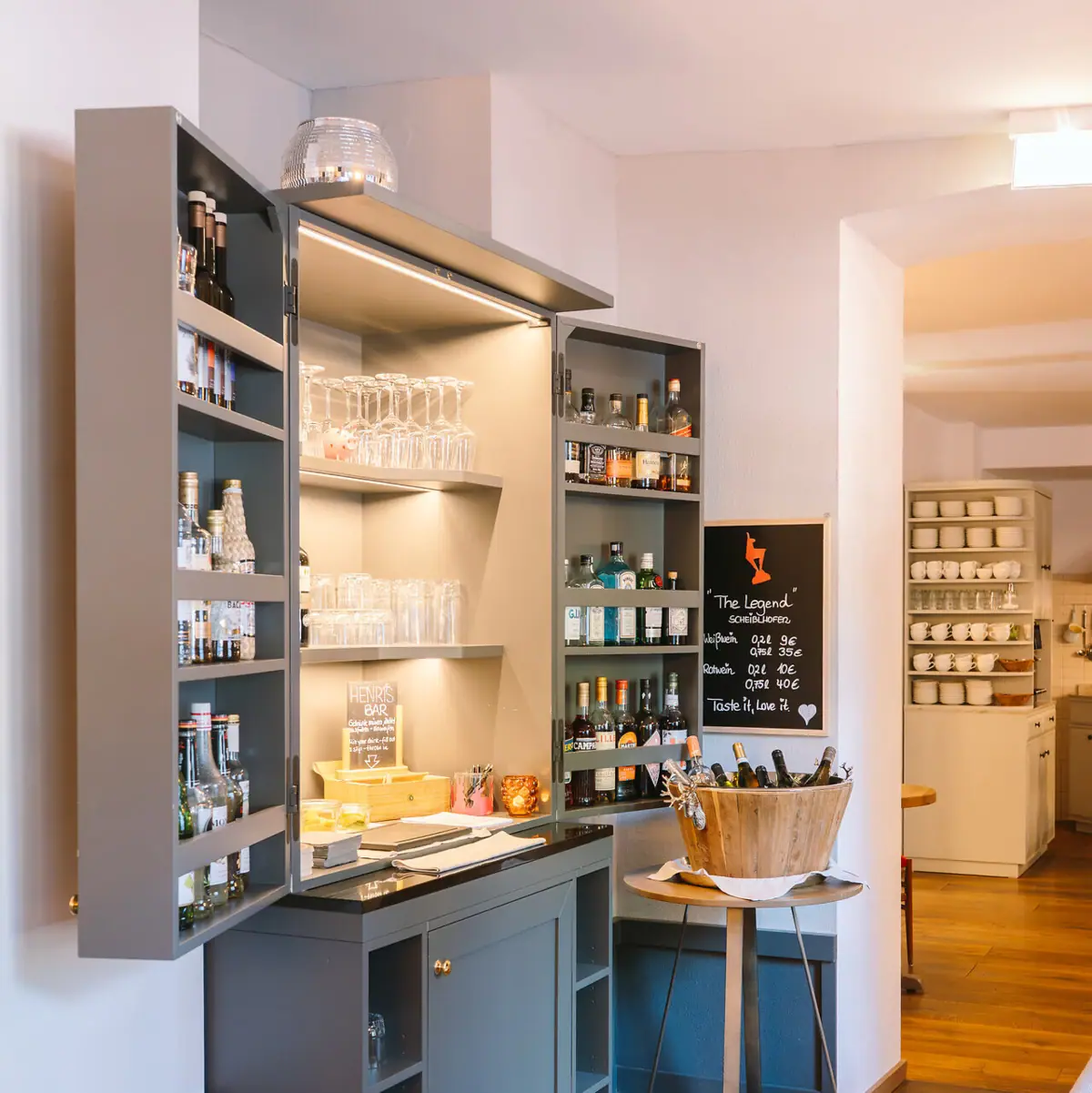 Bar A room with a cupboard and shelves with bottles and glasses.