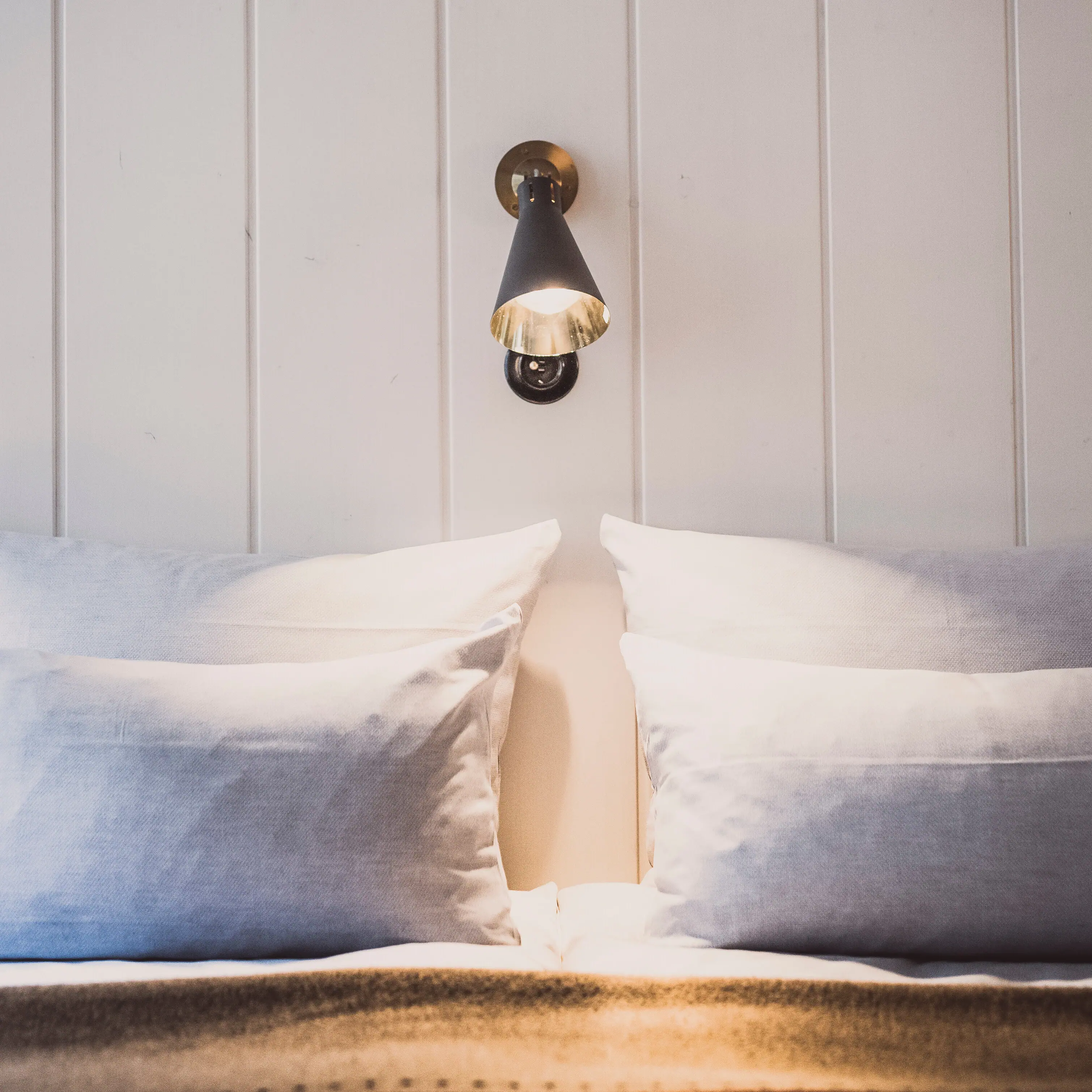 Pillows on a bed Wall lamp above a bed with cushion