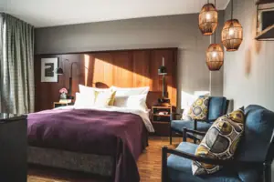 HENRI Hotelroom Düsseldorf A bedroom with a neatly made bed and two chairs.