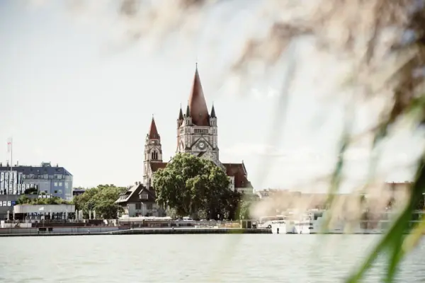 Danube bank A building with a clock tower and trees by the water.