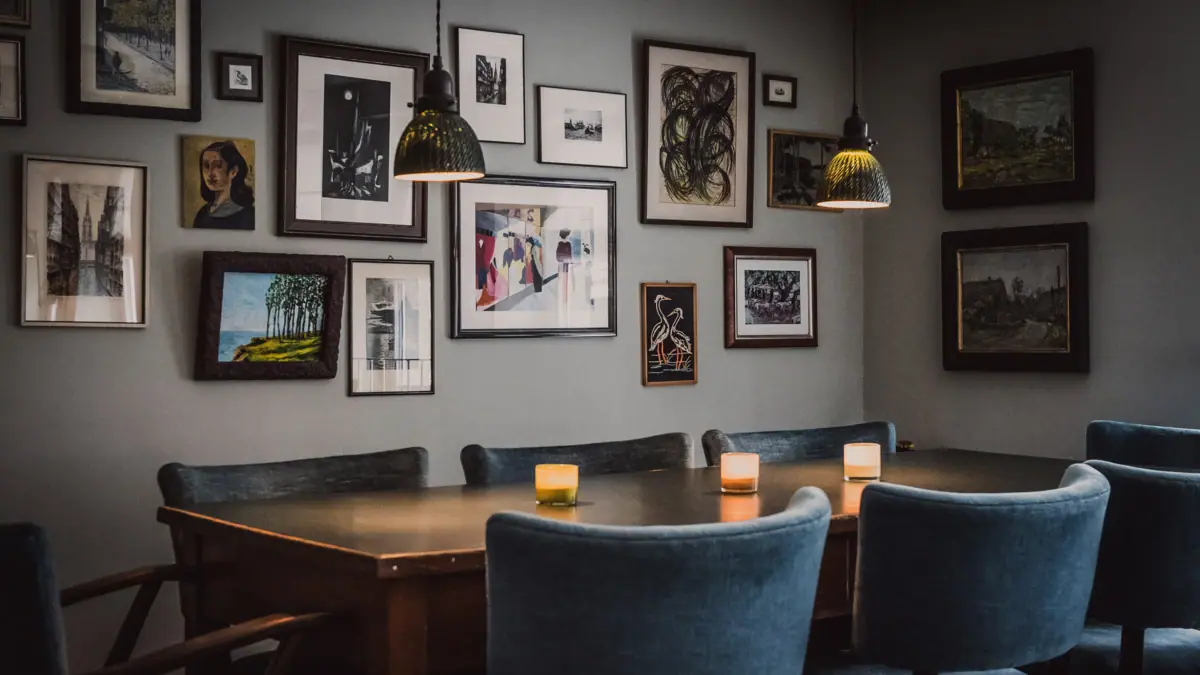Large dining table in office kitchen A table with candles and chairs in the office kitchen with pictures on the wall.