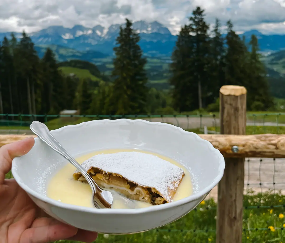 Apfelstrudel One hand holds a bowl of food and a spoon.